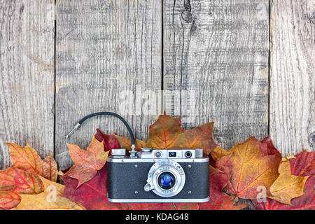 old classic camera on grunge wooden background with colorful dry autumn leaves Stock Photo