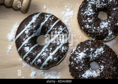 Three chocolate donuts on a wooden base, top view Stock Photo