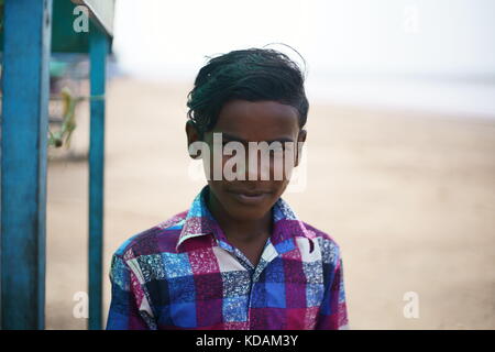 JAMPORE BEACH, DAMAN, INDIA - OCTOBER 9, 2017: A portrait of a young Hard working boy selling Indian fast food & snacks to tourists. Stock Photo