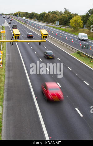 Bright yellow speed cameras in an average speed check area with moving traffic flowing through a roadworks area on a British motorway or carriageway. Stock Photo