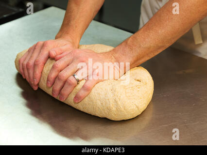 A baker kneading a large dough ball, UK Stock Photo