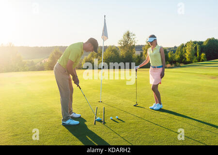 Man ready to hit the golf ball while exercising with his game pa Stock Photo