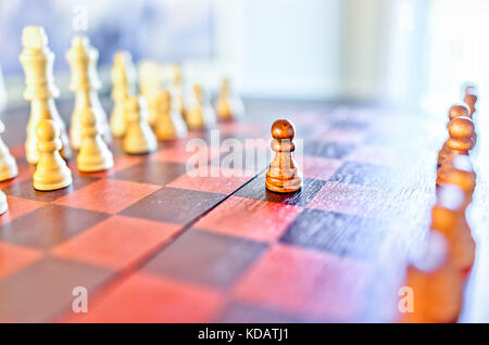 Closeup of chessboard with wooden pieces on table in sunlight and macro focus on pawn Stock Photo