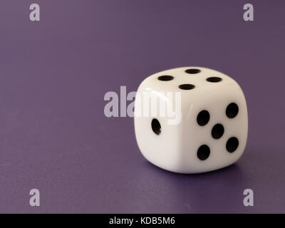Closeup of a single white dice lying on the table Stock Photo