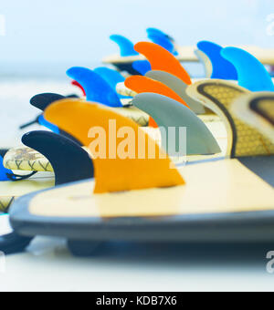 Lots of surfboards laying on the beach, ocean on the background Stock Photo