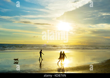 People walking on tropical Bali ocean beach at sunset. Indonesia