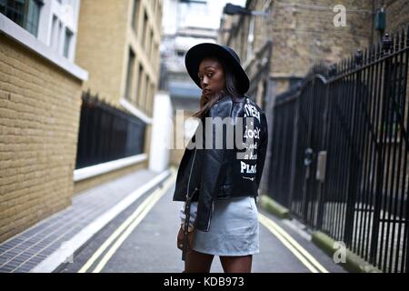 Fashion blogger clad in street style attire strikes a pose amidst an  explosion of graffiti art in a narrow alley