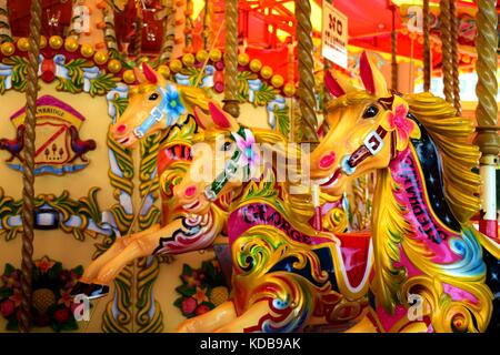Three horses in line on an empty colourful carousel. Bright colours and patterns make the carousel look more beautiful and appealing. Smiling horses. Stock Photo