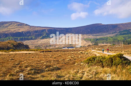 A couple cycling along a quiet narrow road in remote moorland countryside on a beautiful Spring morning. Achfary, Sutherland, Scottish Highlands UK. Stock Photo