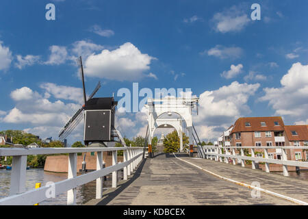 White bridge and historic windmill at a canal in Leiden, Holland Stock Photo