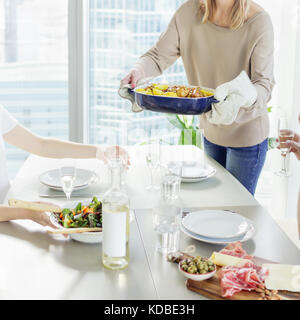 Close-up of woman bringing dish to the table Stock Photo