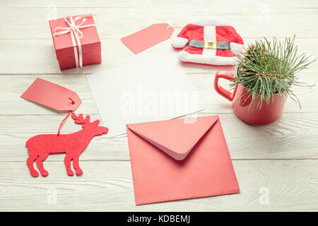 Christmas background of white paper card, red envelop and christmas objects on white wooden background Stock Photo