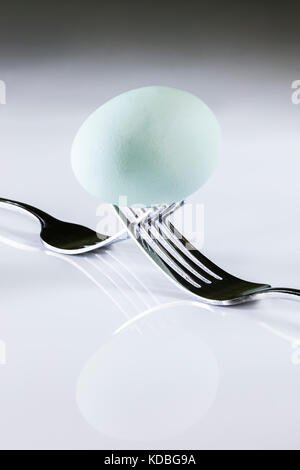 Blue egg balanced on two forks Stock Photo