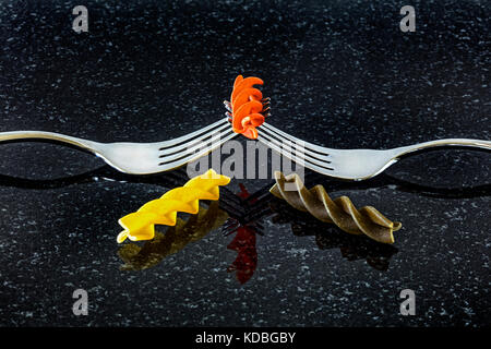 Red yellow and Green fusilli past on fork against a dark background. Stock Photo