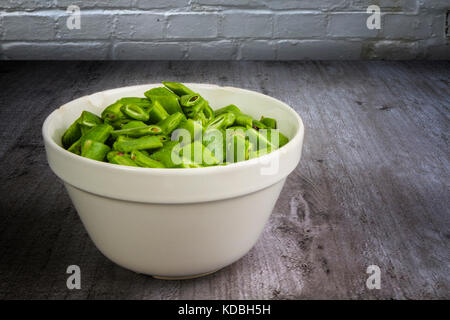 Chopped runner beans in a china bowl on a wooden table Stock Photo