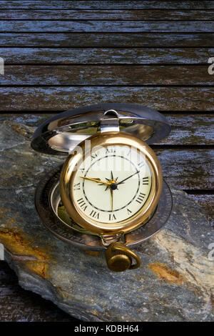 Traditional travelling clock on a piece of slate on a wooden table Stock Photo