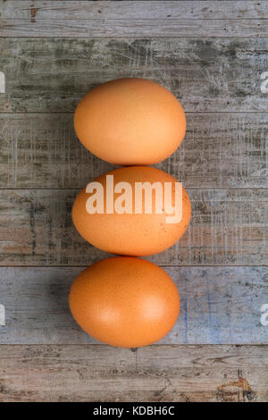 Three brown chicken eggs on a wooden table Stock Photo