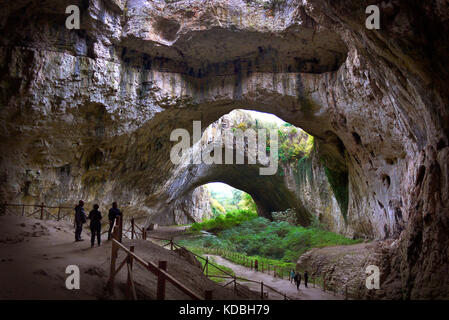 Visitors dwarfed by the size of the Devetashka Cave in Bulgaria. Stock Photo