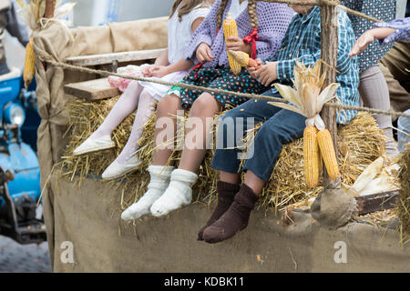Asti, Italy - September 10, 2017: kids grind corn corns sitting on an old wagon Stock Photo