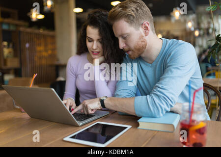 Happy couple spending time at coffee shop working on laptop Stock Photo