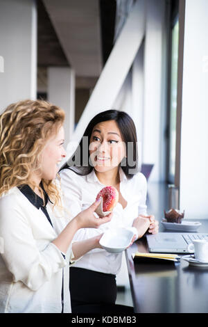 Two female workers in a design studio setting, working together. Caucasian and asian ethnicities. Stock Photo