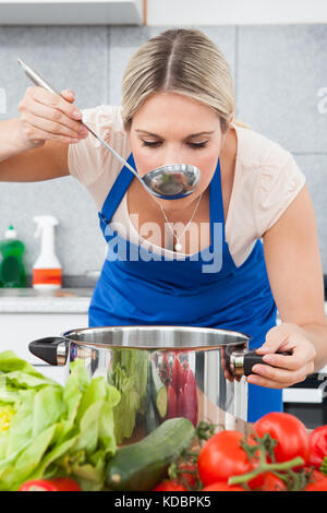 Portrait Of Young Woman Tasting Soup In Kitchen