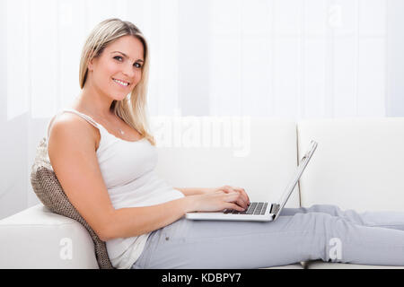 Portrait of Happy Woman Sitting On The Sofa Using Laptop Stock Photo