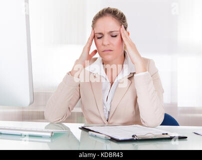 Young Businesswoman Suffering From Headache At Office Stock Photo