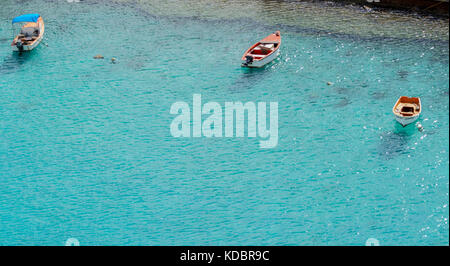 THREE DINGHIES MOORED OFF SHORE Stock Photo