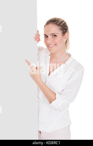 Young woman standing near blank placard and presenting on white background Stock Photo