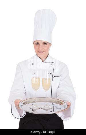 Portrait Of Female Chef Holding Champagne Over White Background Stock Photo