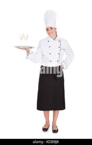 Portrait Of Female Chef Holding Champagne Over White Background Stock Photo