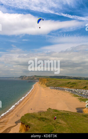 A group of paragliders soaring above the cliffs at Burton Bradstock on the Jurassic Coast, Dorset, England, UK Stock Photo