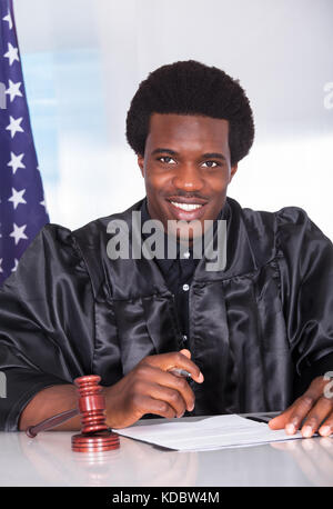 Portrait Of Happy Male Judge Sitting In Courtroom Stock Photo