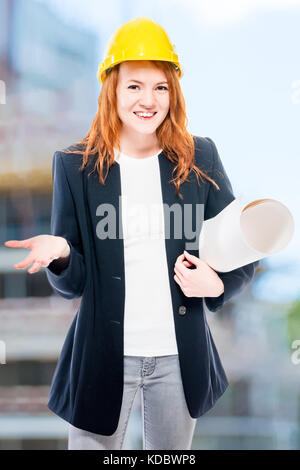 Vertical portrait of a senior architect woman with drawings in a yellow helmet Stock Photo