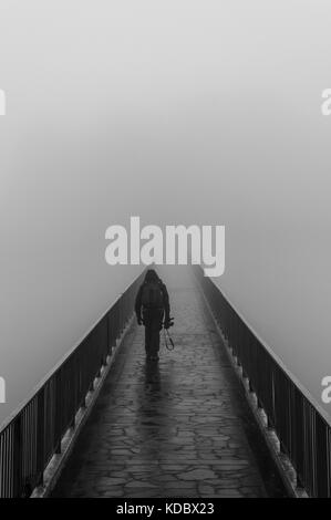 Bridge that crosses the fog with person Stock Photo