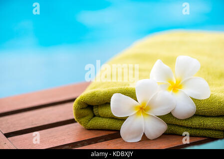 green terry towel on a chaise longue close up and two flowers frangipani Stock Photo