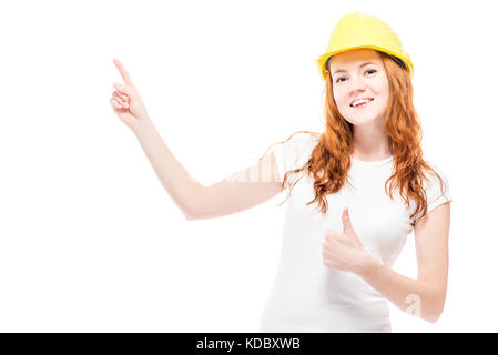 happy woman in a yellow hard hat shows a finger on the space for an inscription Stock Photo