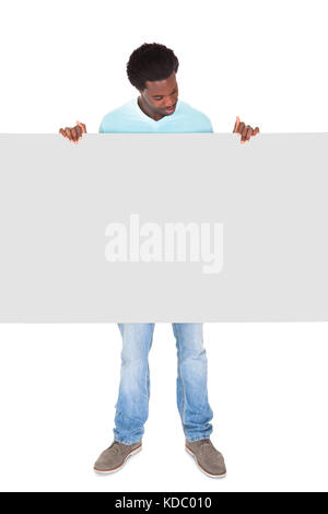 Happy Young African Man In Casual Standing Behind The Placard Over White Background Stock Photo