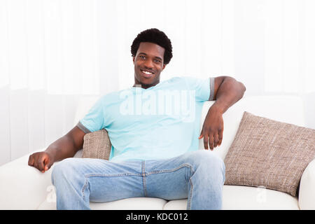 Happy Relaxed Young African Man Sitting On Couch Stock Photo