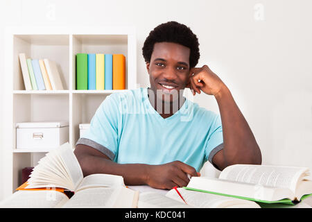 Young African Man Studying At Home With A Lot Of Books Stock Photo