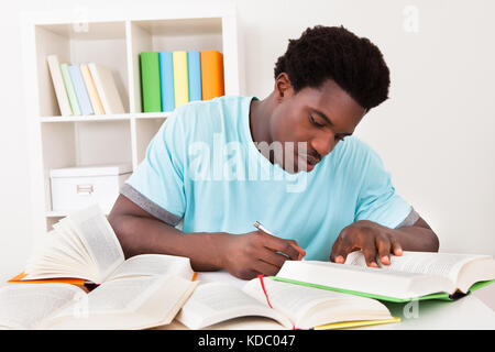 Young African Man Studying At Home With A Lot Of Books Stock Photo