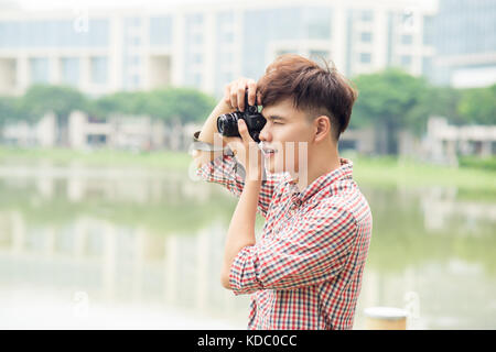 Young smiling man taking picture while walking by the city. Stock Photo