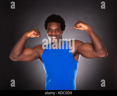 Happy Young African Man Showing Muscle Over Black Background Stock Photo