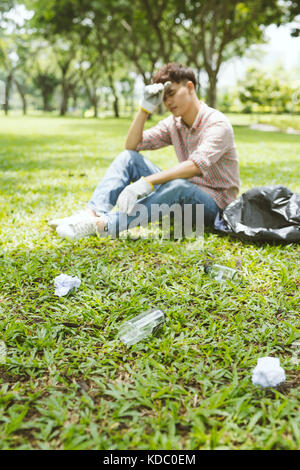Tired man after crouching to waste in the park. Focus on waste. Stock Photo