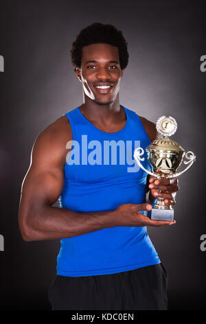 Happy African Man Holding Trophy Over Black Background Stock Photo