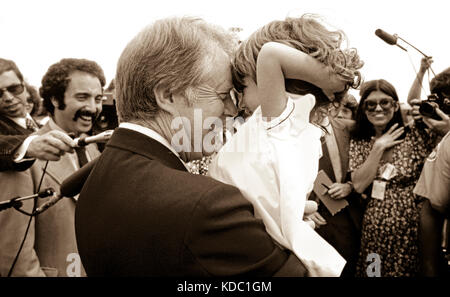 A charmed White House press corps looks on as President Carter rubs noses with a child. Stock Photo