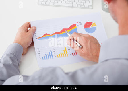 High Angle View Of Businessman Analyzing Graph In Office Stock Photo