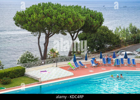 Lacco Ameno, Italy - August 15, 2015: Coastal landscape with ordinary people resting near swimming pool. Ischia, Italy Stock Photo