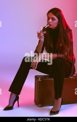 smoking girl sitting on suitcase  Stock Photo